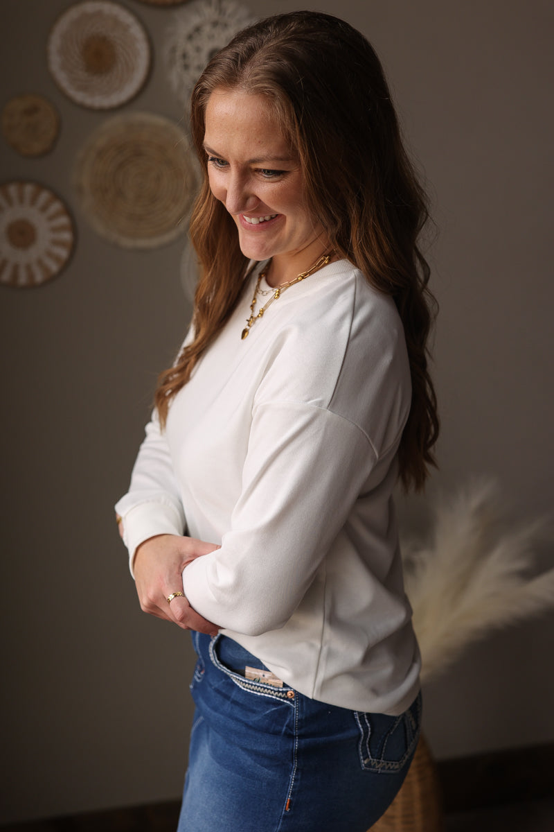 Woman wearing a white long-sleeve shirt and blue jean skirt in a room with decorative plates on the wall.