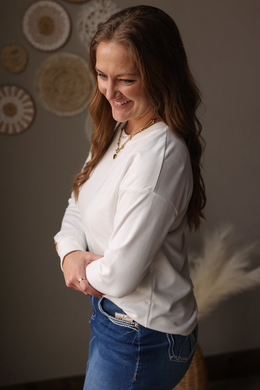 Woman wearing a white long-sleeve shirt and blue jean skirt in a room with decorative plates on the wall.
