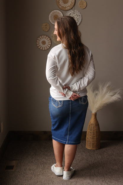 Woman standing in a room with decorative wall art and a vase.