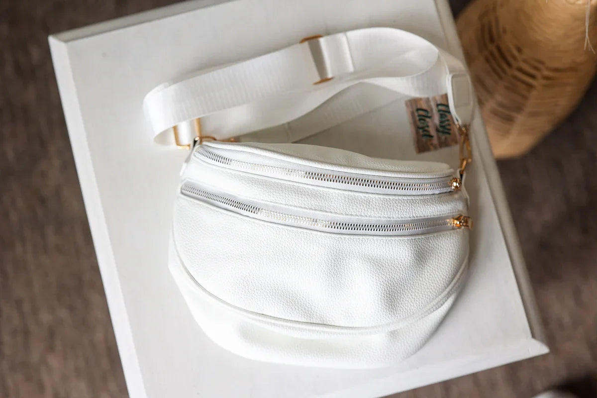 White fanny pack with gold zippers on a white box