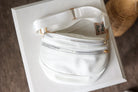 White fanny pack with gold zippers on a white box