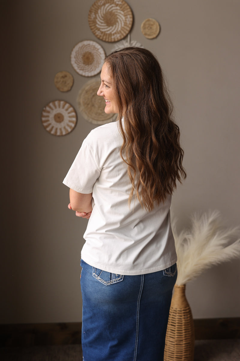 Woman standing in a room with decorative plates on the wall and a basket with dried plants.