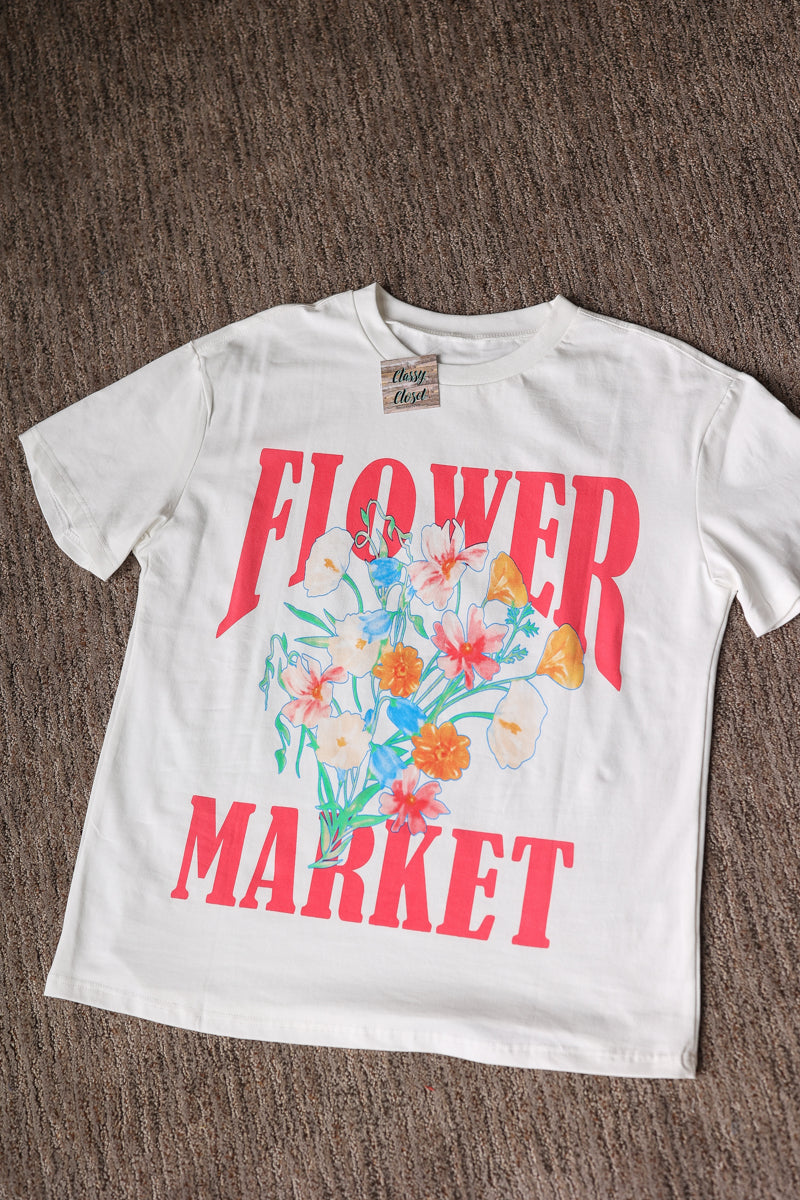 White t-shirt with 'Flower Market' graphic on a brown surface