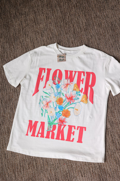 White t-shirt with 'Flower Market' graphic on a brown surface