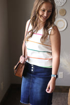 Woman wearing a striped tank top and blue skirt indoors.