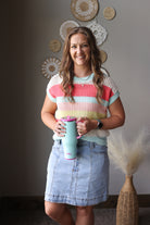 Woman holding a tumbler in a room with decorative wall art