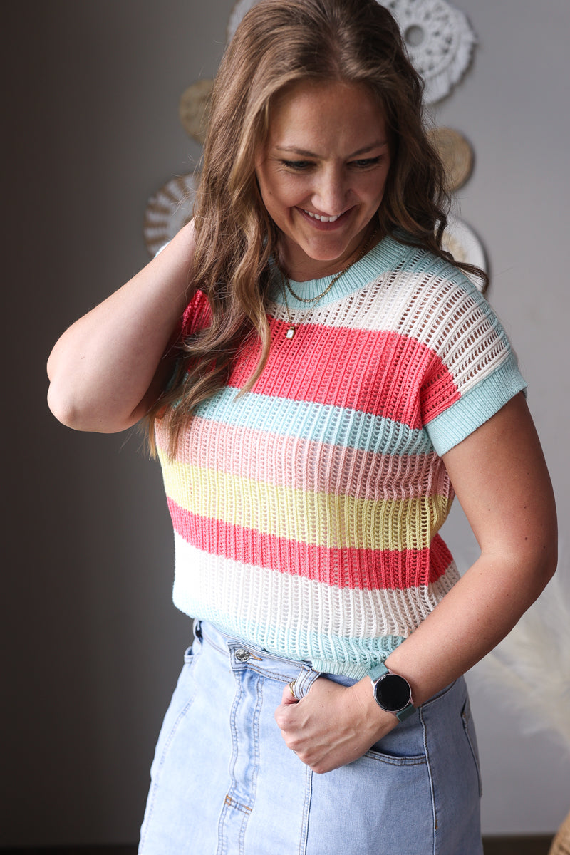 Woman wearing a colorful striped sweater with a neutral background