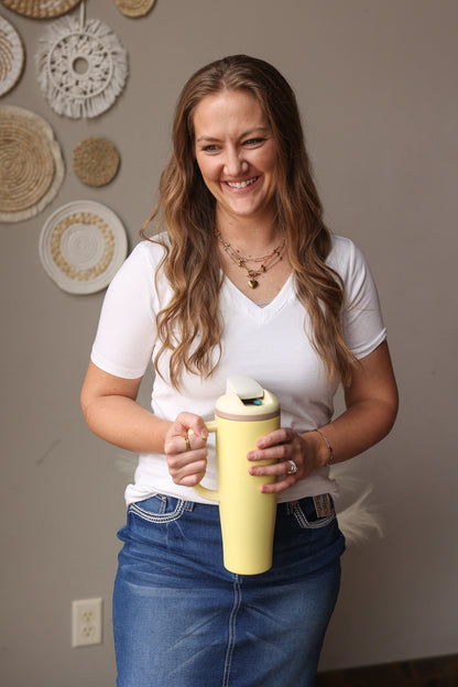 Woman holding a yellow mug in a room with decorative plates on the wall.